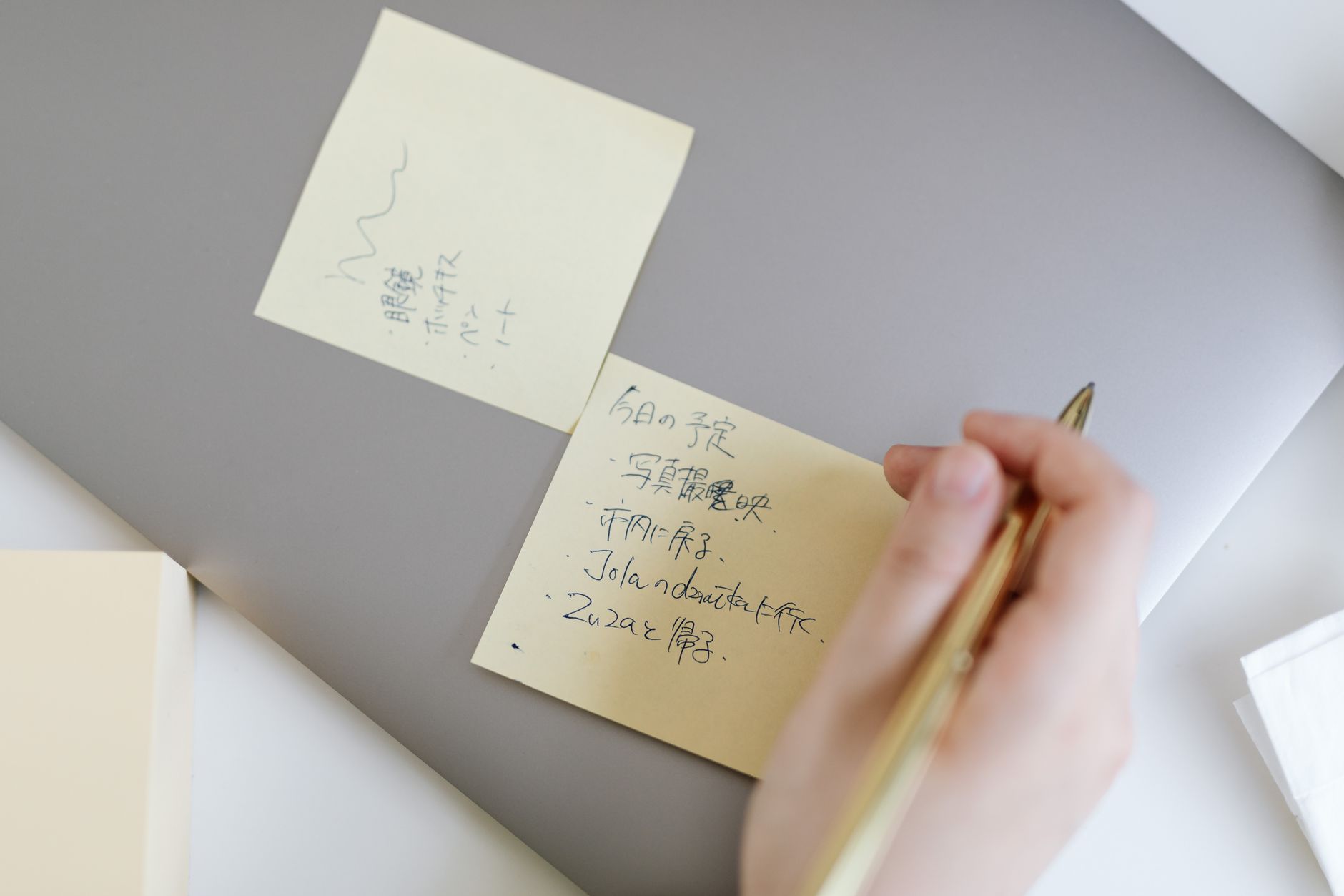Hand writes a personal note on a sticky note.